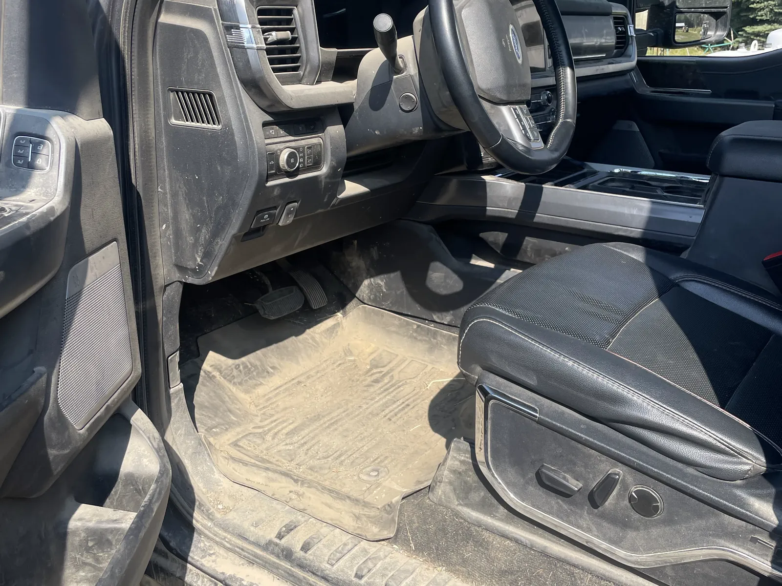 A Ford Super Duty footwell before: mats and sill buried under dried dust.