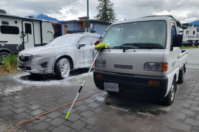 A Mazda CX-5 under snow foam on a Pemberton driveway, the Duty Duck kei truck alongside.