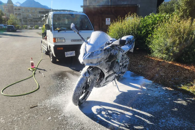 A sport bike covered in snow foam on a sunny morning next to the kei truck.